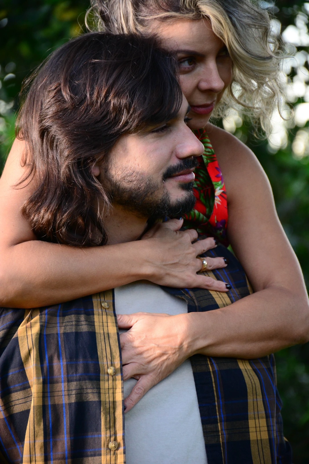 Pareja abrazada al aire libre, ella lo rodea con los brazos por la espalda